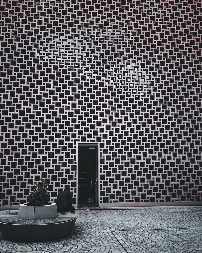 Contemporary building facade with intricate geometric design and single door.