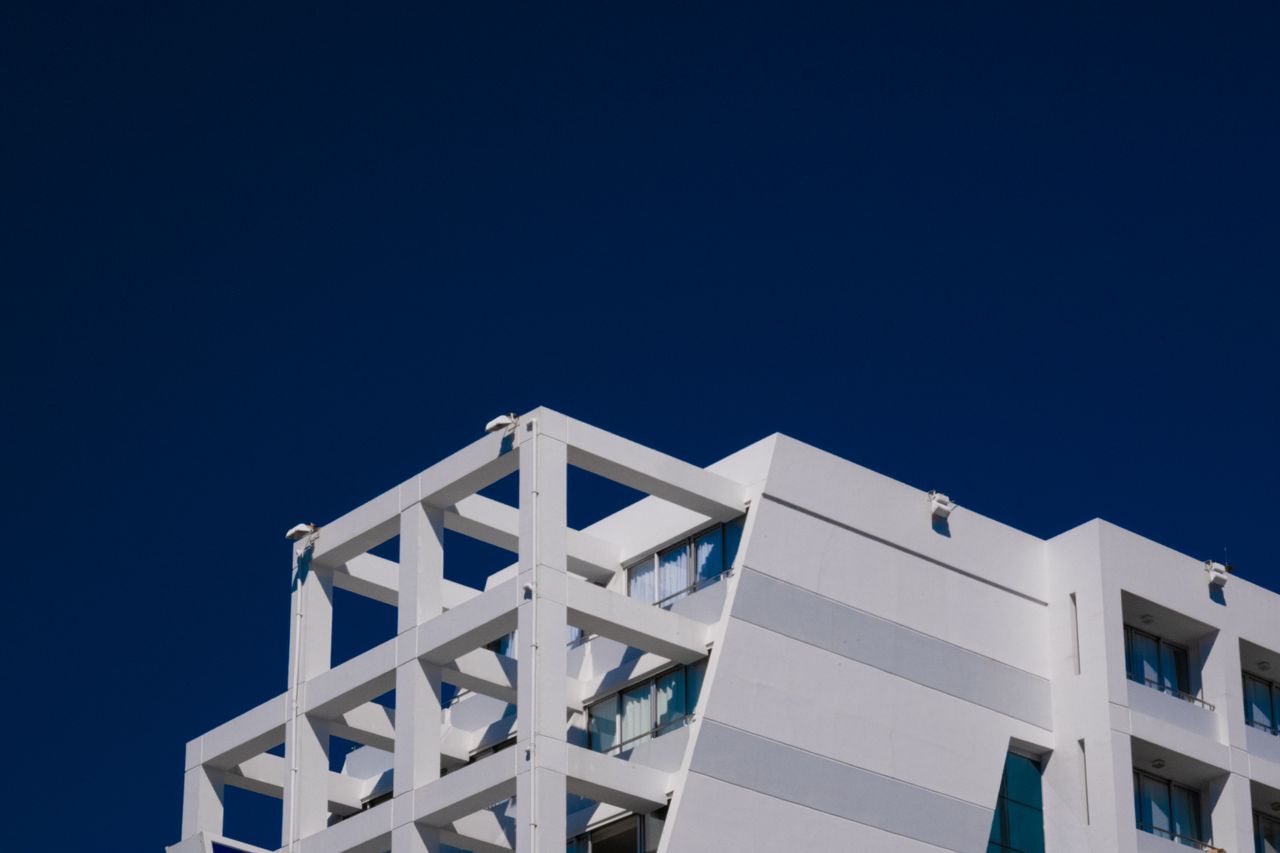 The Art of Drawing Readers In: Your attractive post title goes here A modern white building with geometric design set against a clear blue sky.