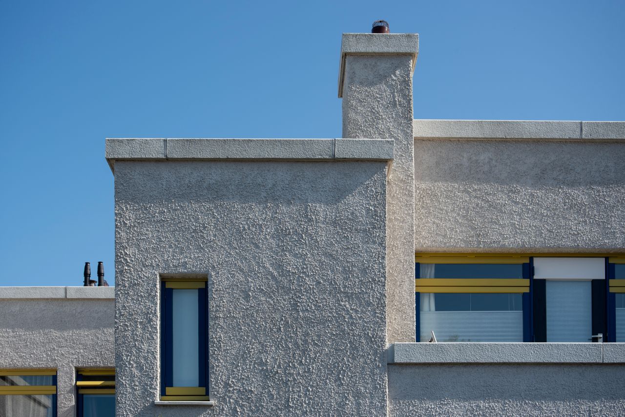 Home Close-up of a modern concrete building facade against a blue sky. Minimalist architectural design.