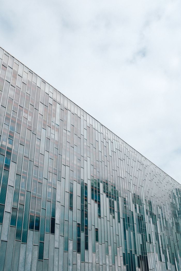 Sleek architectural design featuring vertical glass panels under a cloudy sky.